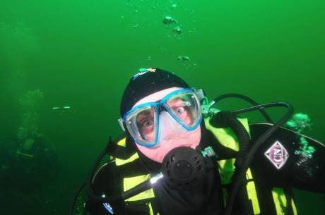 Scuba diver in green water looking at the camera